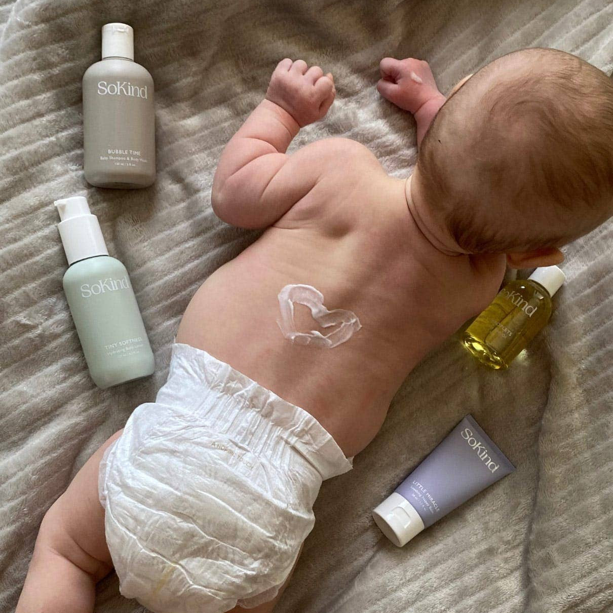 Baby lying on a textured surface with skincare products around