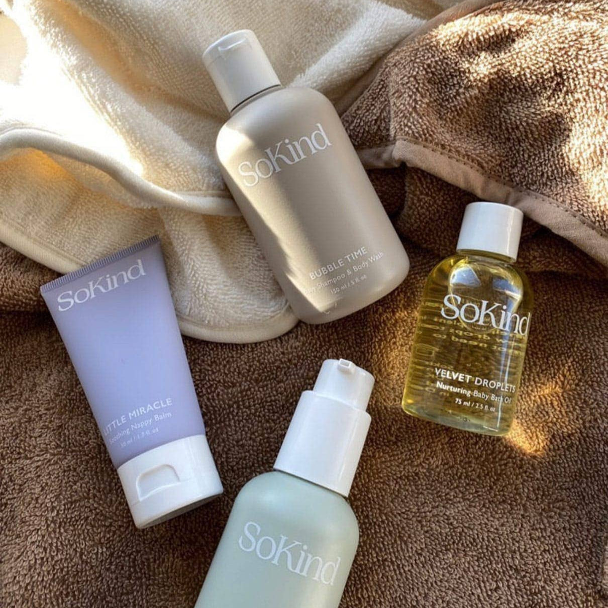 Set of SoKind skincare products on a textured fabric background